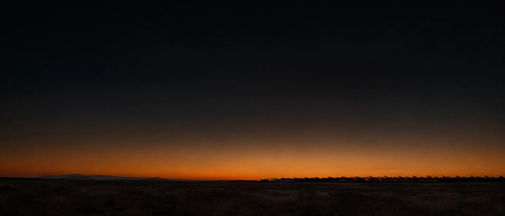 High plains at dusk with backlit solar infrastructure