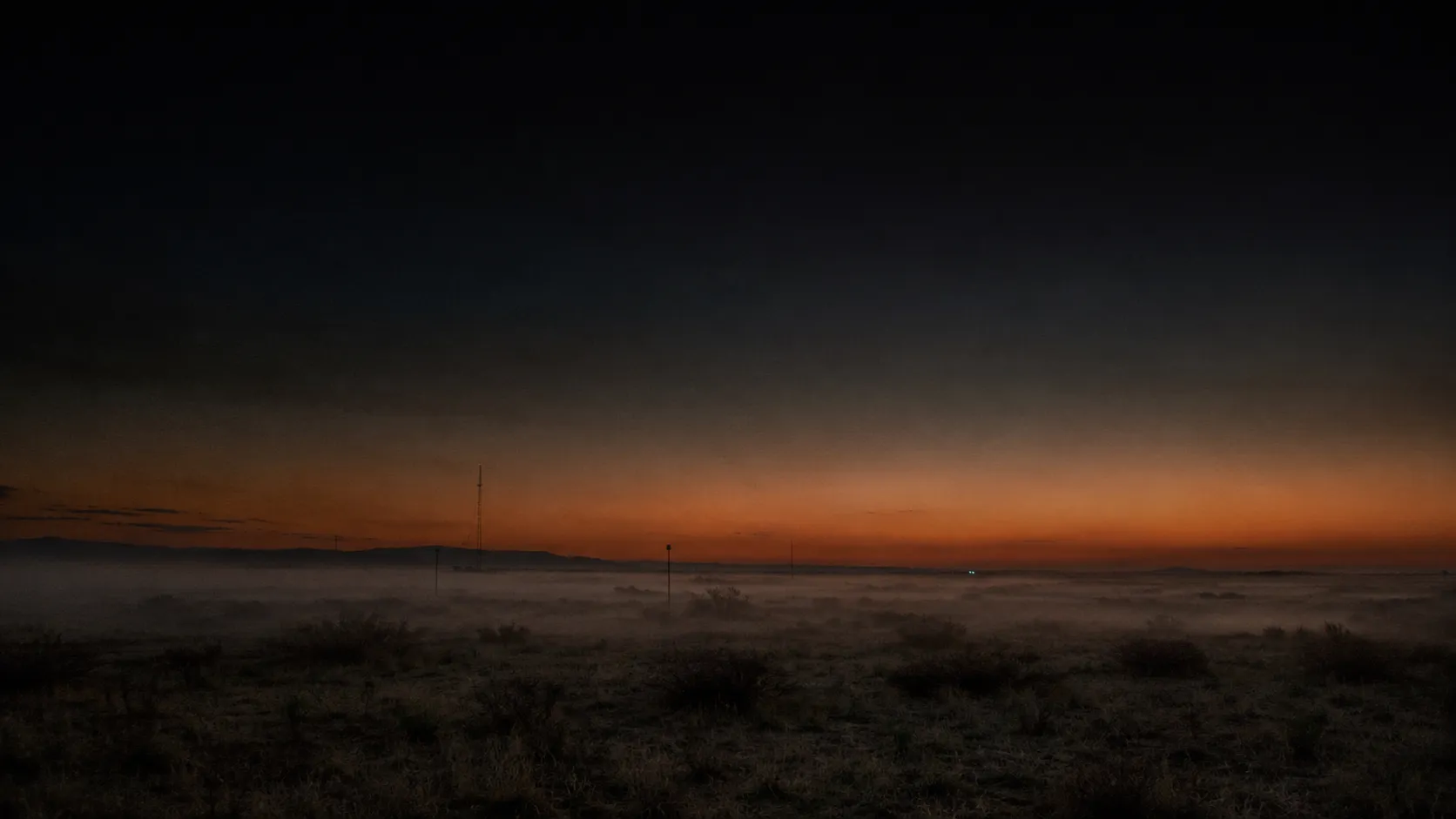 Open field at nightfall with telemetry antennas in low fog